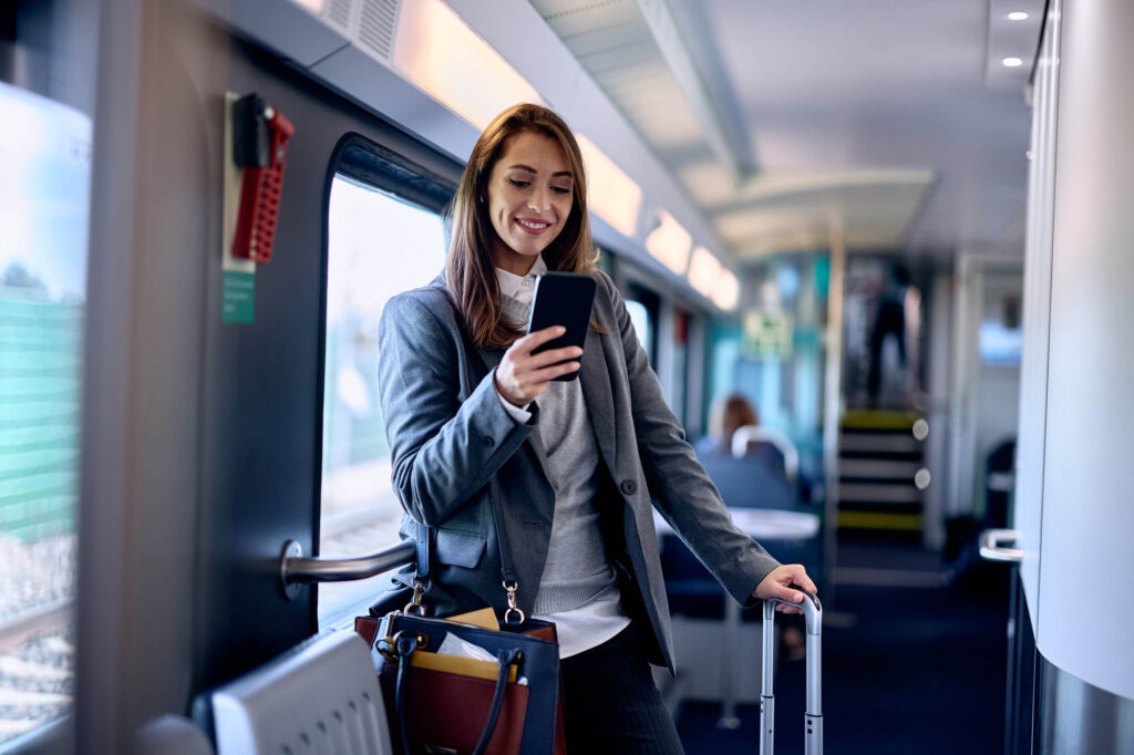 Happy woman using smart phone while traveling by train.